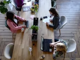 Three Woman Sitting on White Chair in Front of Table