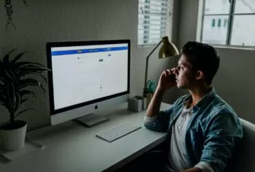 man in blue denim jacket facing turned on monitor