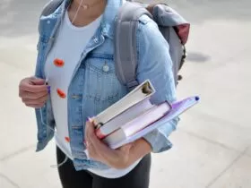 woman wearing blue denim jacket holding book