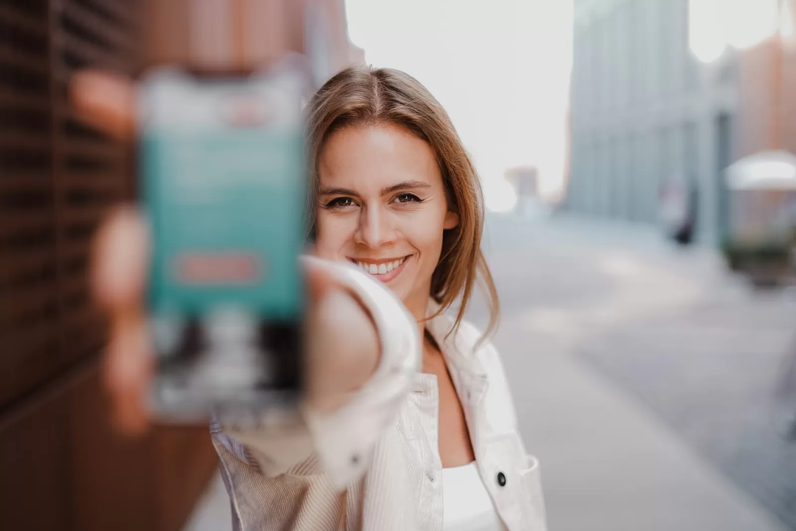 woman in white coat holding green box