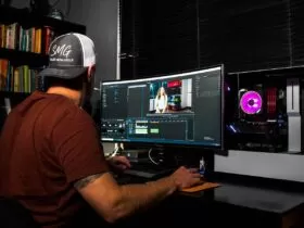 man in red t-shirt sitting in front of computer