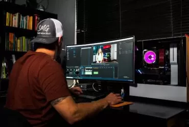 man in red t-shirt sitting in front of computer