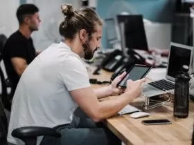 man holding turned-on iPad in front of turned-off MacBook Air