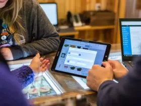 two people sitting at a table looking at a tablet