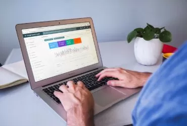 person using macbook air on white table