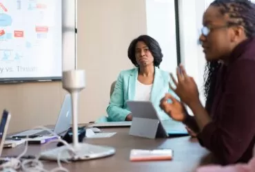 selective focus photography of woman in gray blazer looking at woman in black top